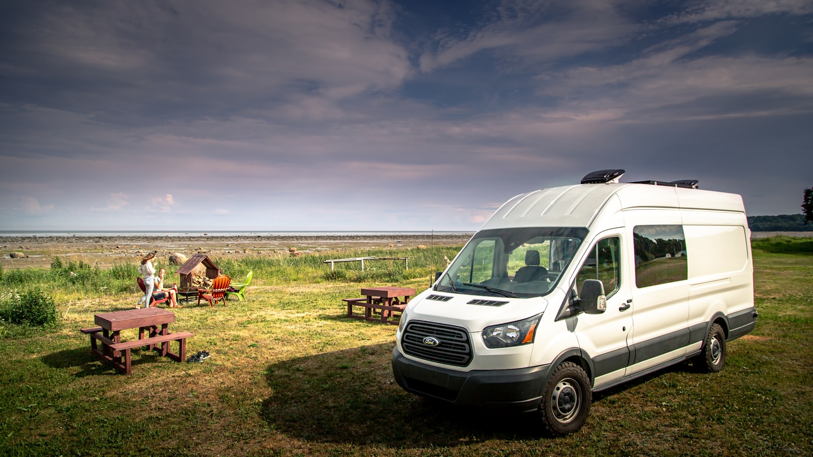 A white passenger shuttle van parked by a grassy shoreline (placeholder photo)